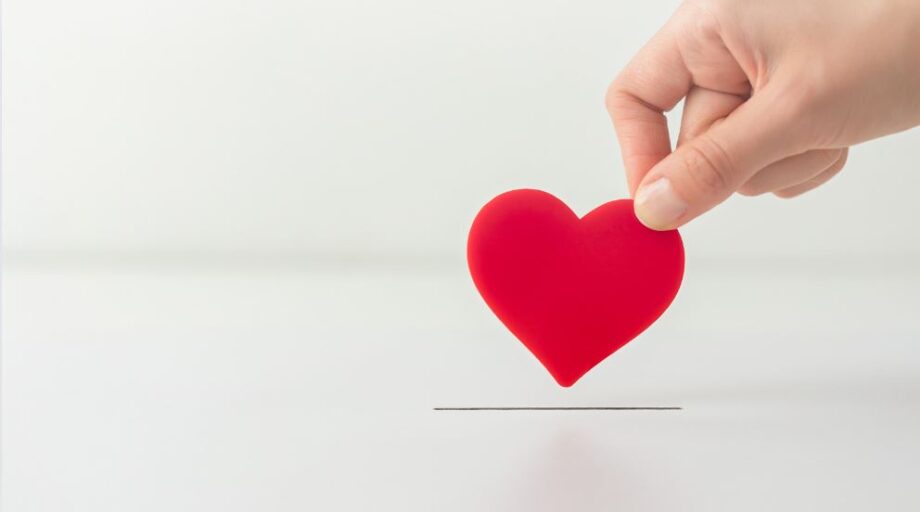 Hand Holding Heart Donating it for Charity on White Background